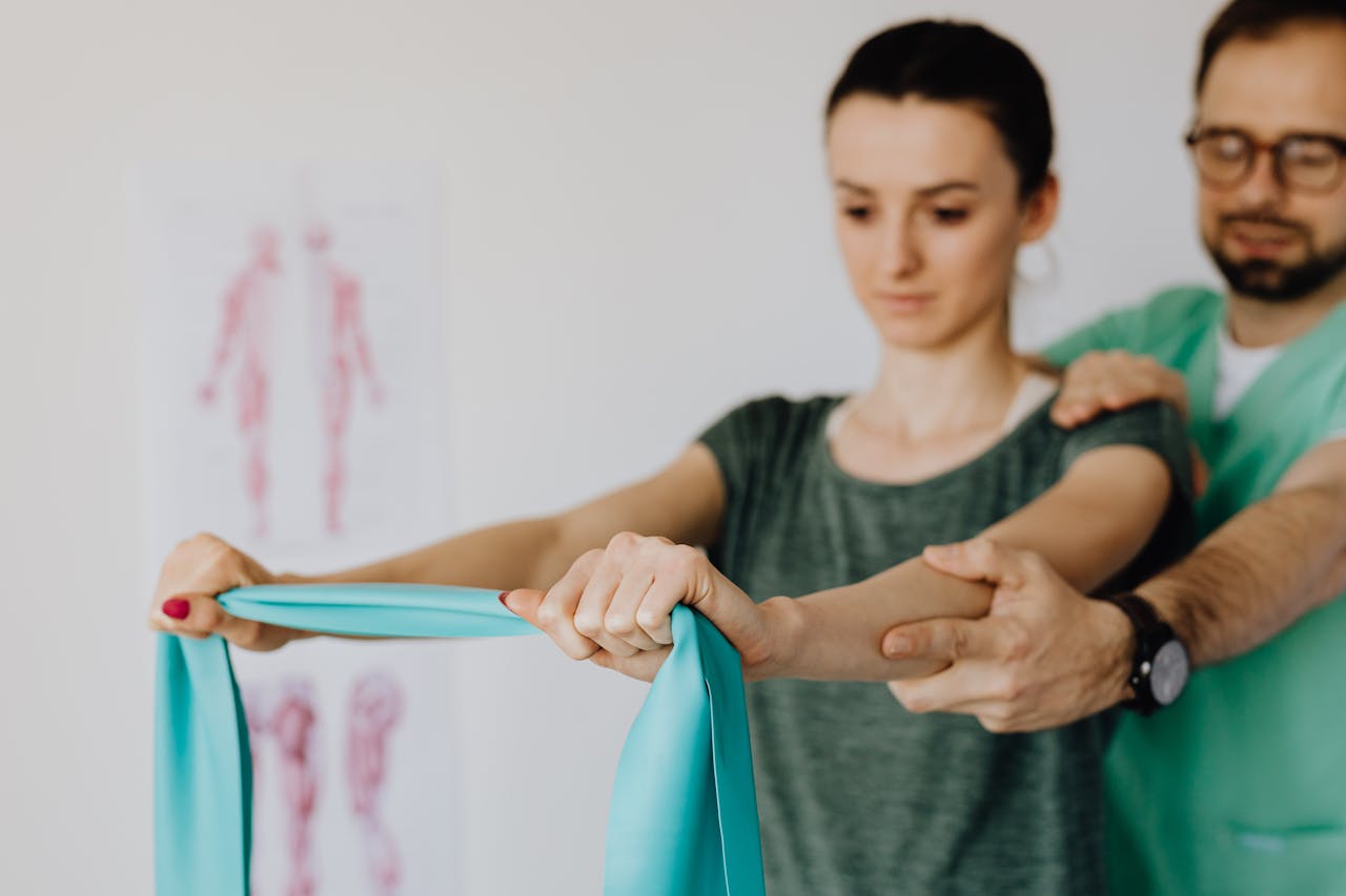 A young woman receives physical therapy assistance, using a stretching band for rehabilitation.